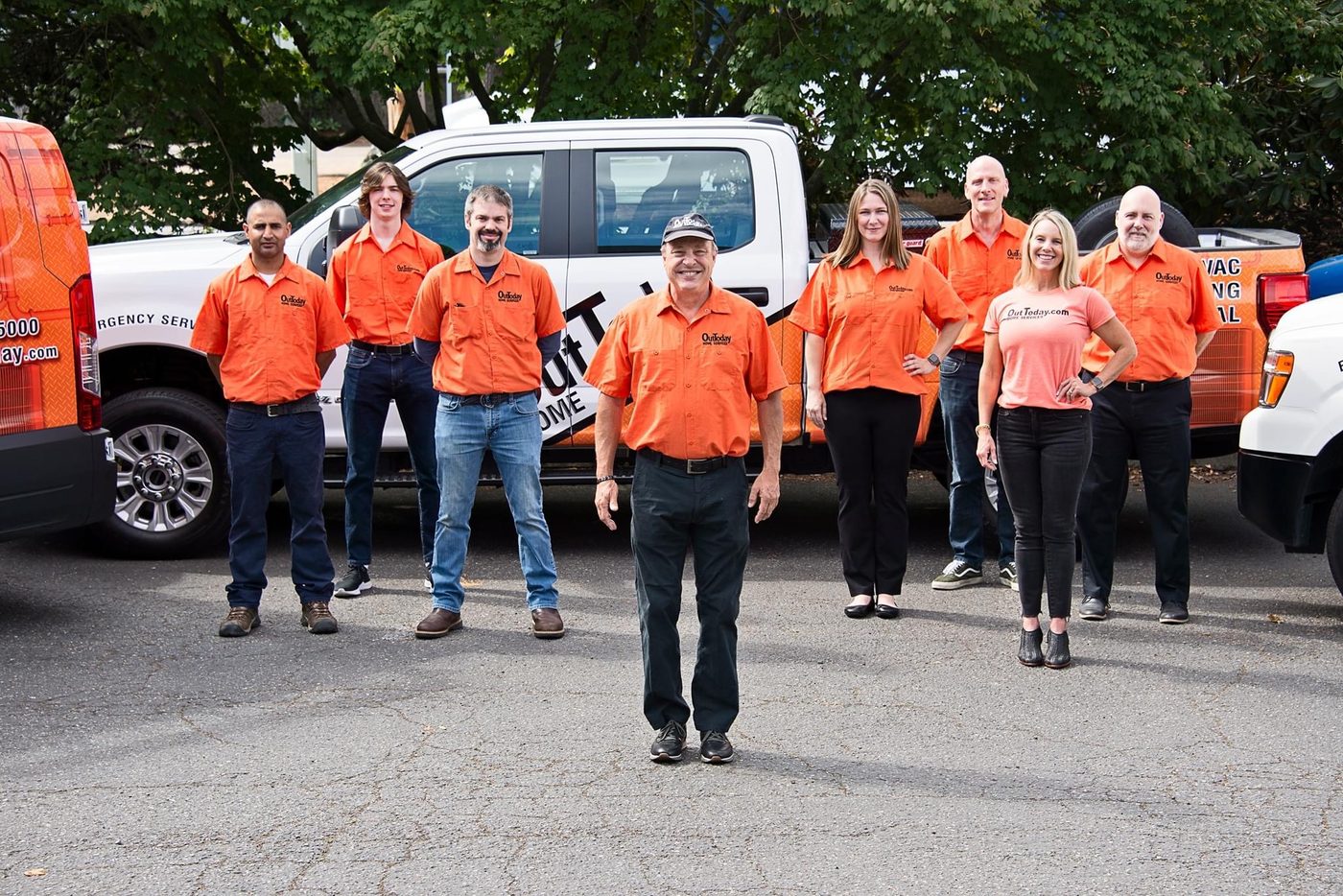 The OutToday team standing in front of the company service trucks